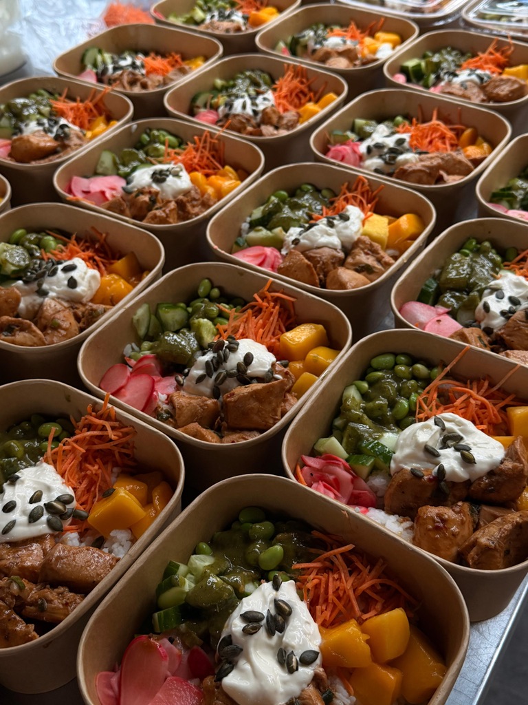 Rijen verse bowls met kip, mango en edamame voor een vergaderlunch